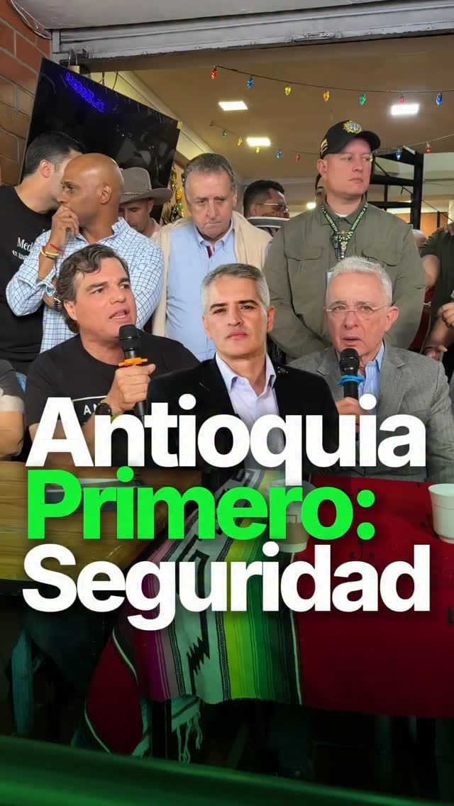 Alejandro Arbeláez A. habla con micrófono en un salón lleno, junto a Álvaro Uribe Vélez; texto «Antioquia Primero: Seguridad»